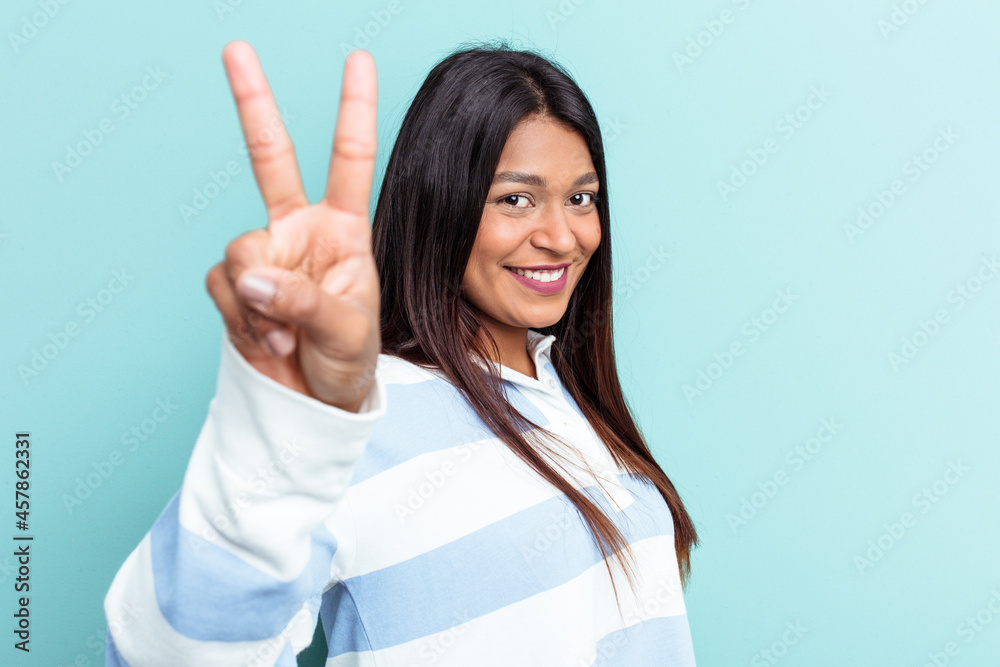 Young Venezuelan woman isolated on blue background showing victory sign and smiling broadly. Young Venezuelan woman isolated on blue background showing victory sign and smiling broadly.