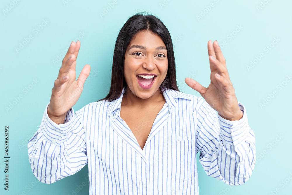 Young Venezuelan woman isolated on blue background receiving a pleasant surprise, excited and raising hands. Young Venezuelan woman isolated on blue background receiving a pleasant surprise, excited and raising hands.
