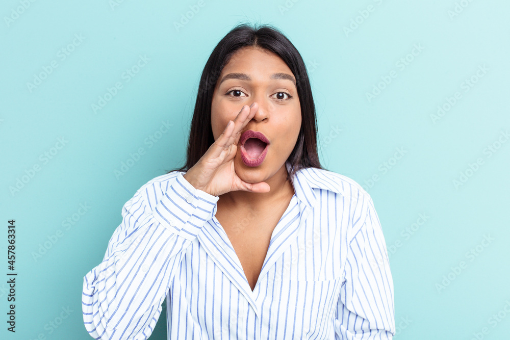 Young Venezuelan woman isolated on blue background is saying a secret hot braking news and looking aside Young Venezuelan woman isolated on blue background is saying a secret hot braking news and looking aside