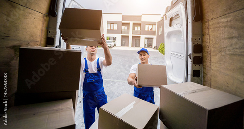 Two removal company workers unloading boxes from minibus photo