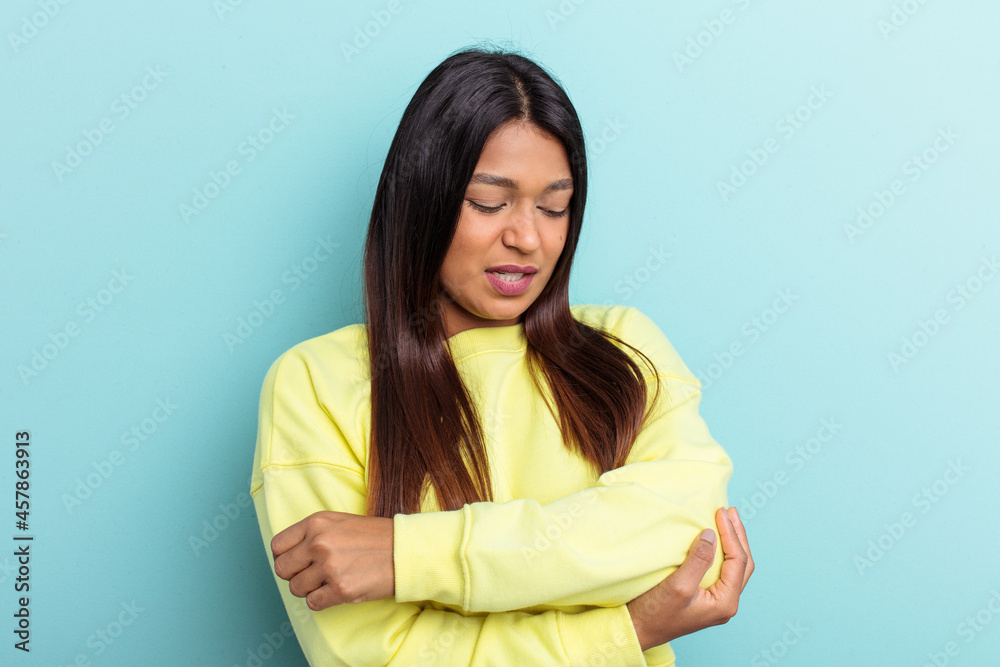 Obraz premium Young Venezuelan woman isolated on blue background massaging elbow, suffering after a bad movement.
