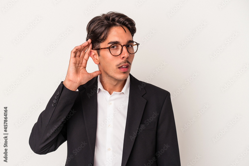 Young mixed race business man isolated on white background trying to listening a gossip. Young mixed race business man isolated on white background trying to listening a gossip.