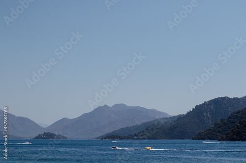 Clear blue sea with mountain views under blue sky with passing boats