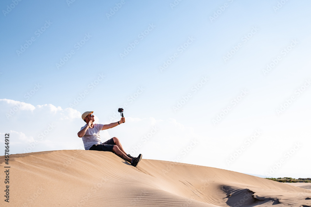 Man sitting and taking selfies on sand dune Man sitting and taking selfies on sand dune