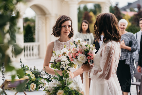 Obraz na płótnie Portrait of two loving female lesbian LGBT brides telling their marriage vows at the wedding ceremony in front of wedding officiant