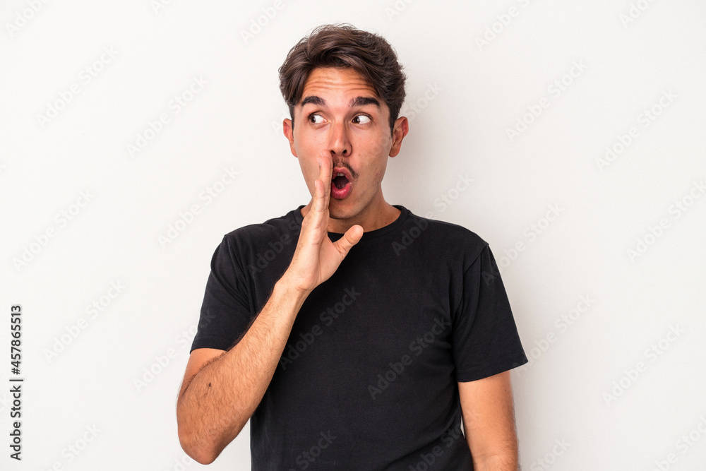 Young mixed race man isolated on white background is saying a secret hot braking news and looking aside Young mixed race man isolated on white background is saying a secret hot braking news and looking aside