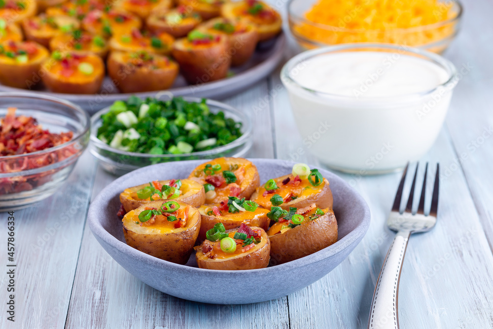 Mini red skinned loaded potatoes with crispy bacon, scallions and sharp cheddar cheese, closeup