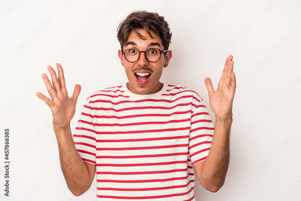 Young mixed race man isolated on white background receiving a pleasant surprise, excited and raising hands. Young mixed race man isolated on white background receiving a pleasant surprise, excited and raising hands.