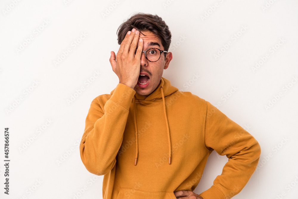 Young mixed race man isolated on white background having fun covering half of face with palm. Young mixed race man isolated on white background having fun covering half of face with palm.