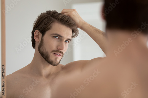 Print op canvas Young shirtless guy looks in mirror touch hair feels concerned due to receding, dry, dull hair