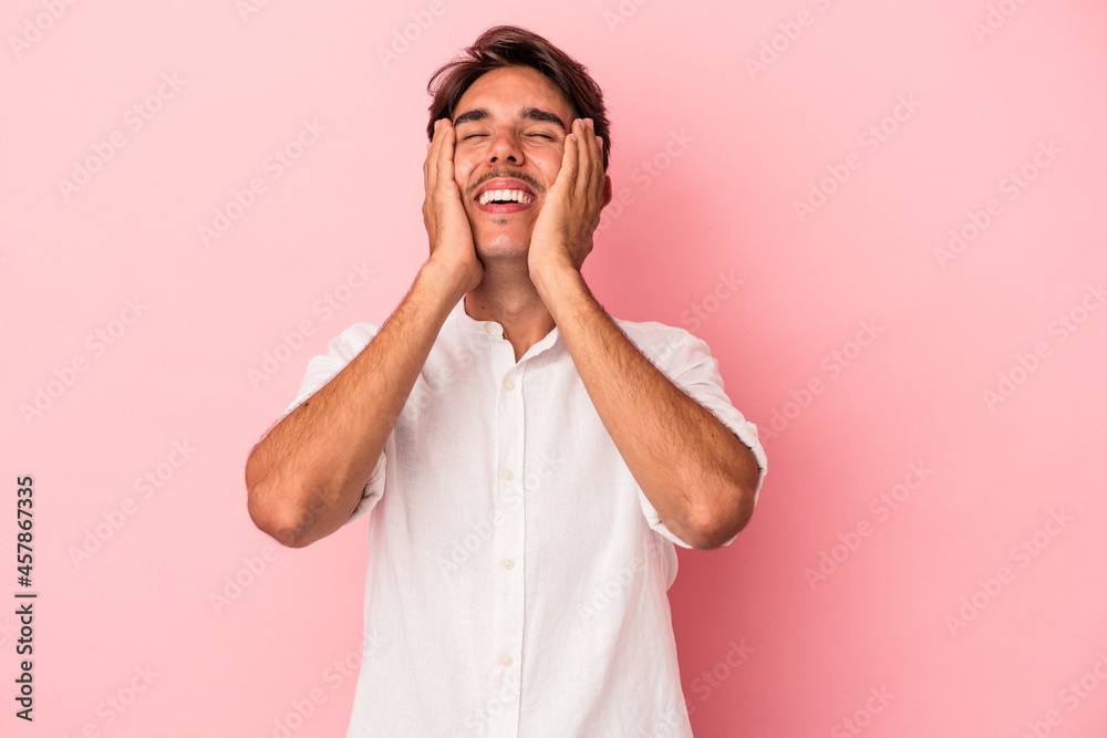 Young mixed race man isolated on white background laughs joyfully keeping hands on head. Happiness concept. Young mixed race man isolated on white background laughs joyfully keeping hands on head. Happiness concept.