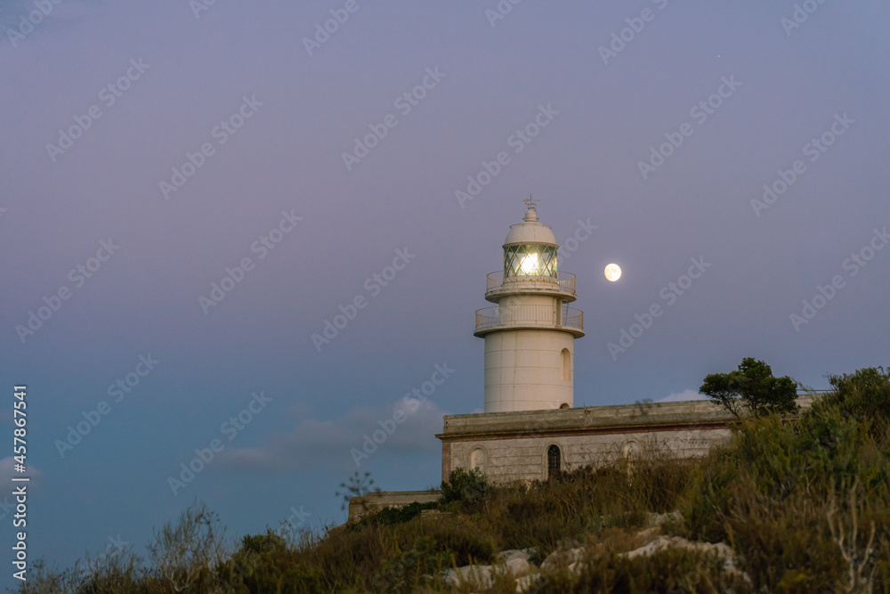 San Antonio's Cape lighthouse at dusk, with the moon in the sky.