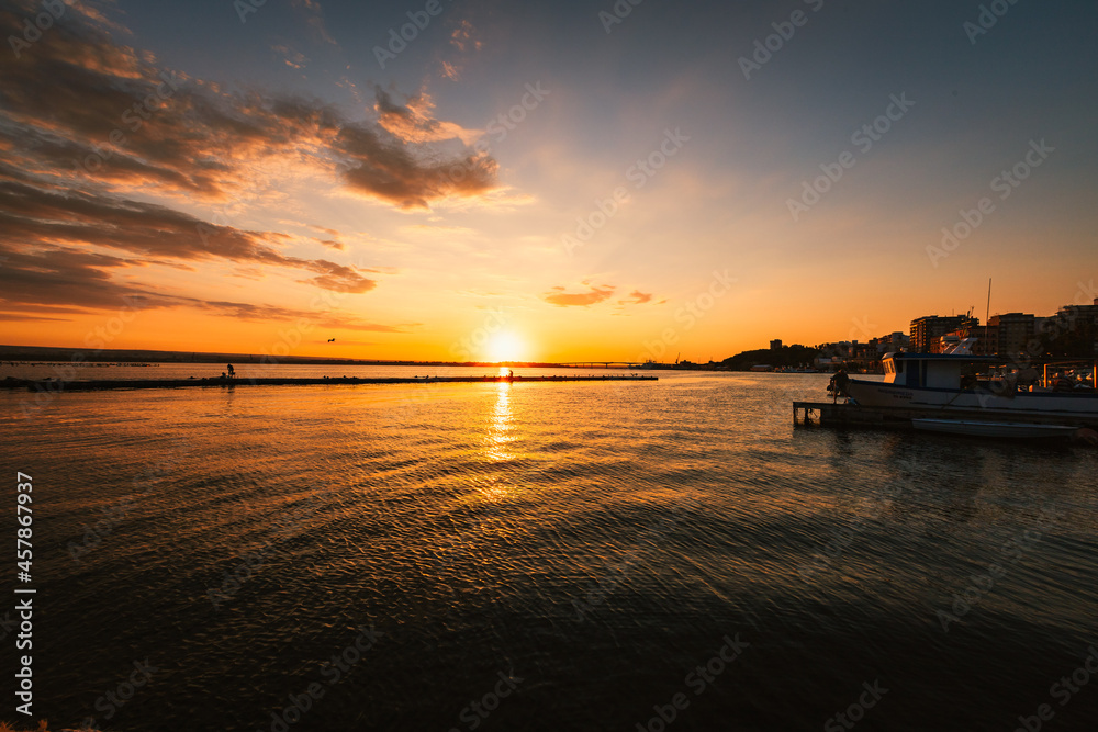 Port of the village of Taranto Vecchia at dawn with silhouettes of fishermen