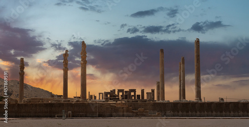 Ruins of Apadana and Tachara Palace behind stairway with bas relief carvings in Persepolis UNESCO World Heritage Site against cloudy sunset sky in Shiraz city of Iran. photo