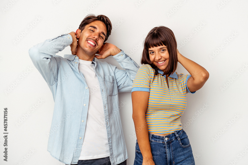 Fototapeta premium Young mixed race couple isolated on white background stretching arms, relaxed position.