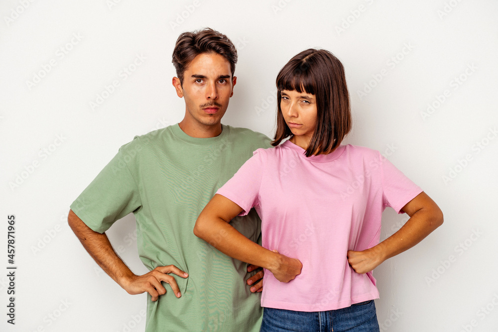 Young mixed race couple isolated on white background frowning face in displeasure, keeps arms folded. Young mixed race couple isolated on white background frowning face in displeasure, keeps arms folded.