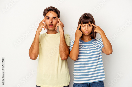 Young mixed race couple isolated on white background focused on a task, keeping forefingers pointing head.