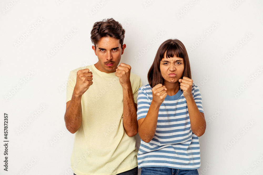 Young mixed race couple isolated on white background showing fist to camera, aggressive facial expression. Young mixed race couple isolated on white background showing fist to camera, aggressive facial expression.