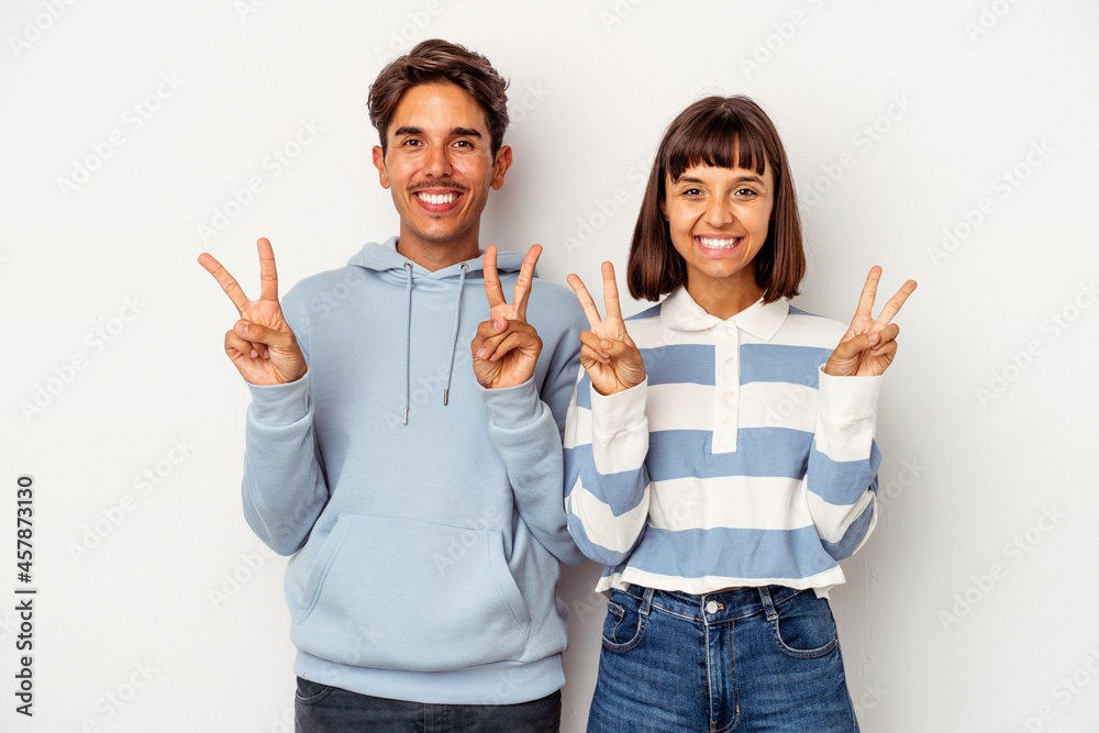 Young mixed race couple isolated on white background showing victory sign and smiling broadly. Young mixed race couple isolated on white background showing victory sign and smiling broadly.