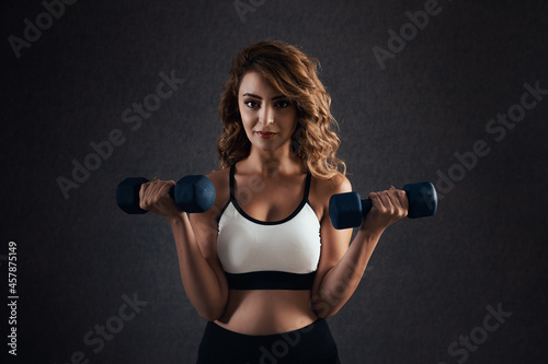 Beautiful woman is lifting dumbbells for a fit body and healthy life