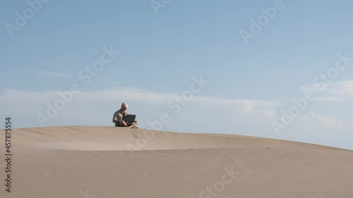 Man works on laptop in the desert. Digital nomad and remote worker concept photo