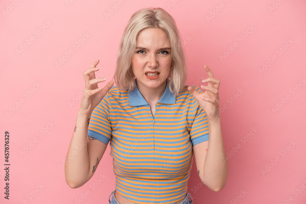 Young caucasian woman isolated on pink background upset screaming with tense hands.