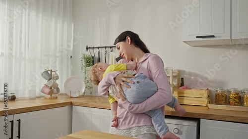 Caucasian busy mother doing hold baby boy toddler to lull him to sleep