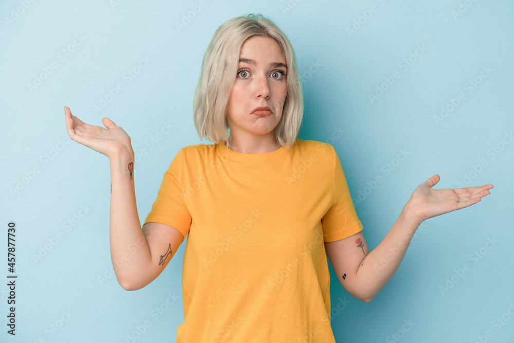 Young caucasian woman isolated on blue background doubting and shrugging shoulders in questioning gesture. Young caucasian woman isolated on blue background doubting and shrugging shoulders in questioning gesture.