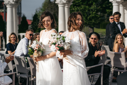 Candid shot of two female lesbian LGBT brides walking through guests photo