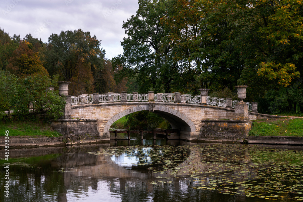 View of the Slavyanka River and the Viscontiev Bridge in the Pavlovsk Palace and Park Complex on a cloudy autumn morning, Pavlovsk, Saint Petersburg, Russia