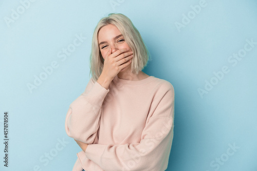 Young caucasian woman isolated on blue background laughing happy, carefree, natural emotion.