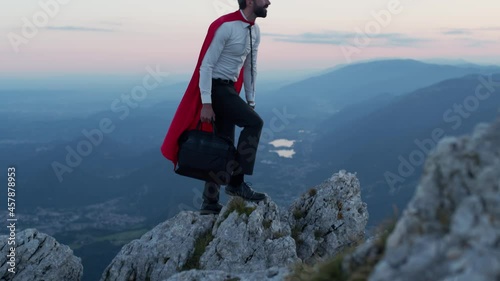 Businessman with the mantle of a superhero over the mountain.