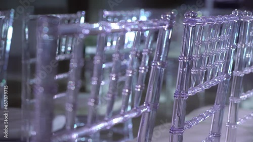 White transparent plastic Chiavari chairs in rows. Indoor wedding ceremony.