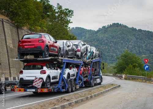 Car transporter transports new cars to the showroom. Cars arranged on two levels. Cars of different colors.No logo or brand.