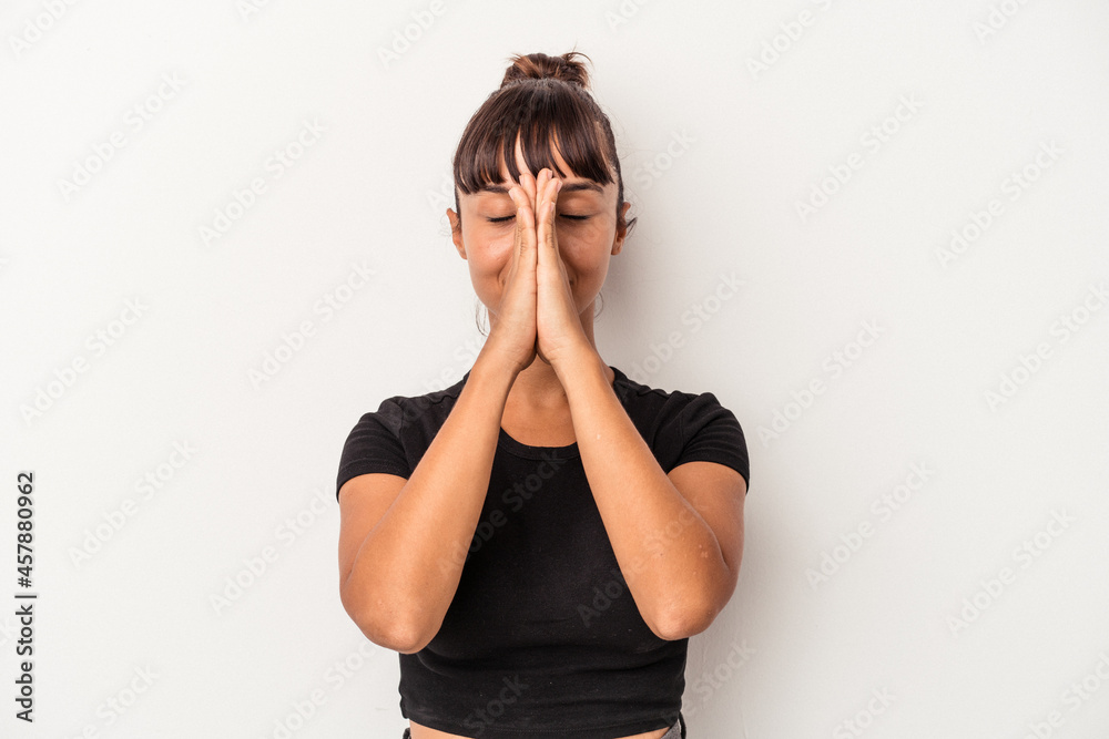 Young mixed race woman isolated on white background holding hands in pray near mouth, feels confident. Young mixed race woman isolated on white background holding hands in pray near mouth, feels confident.