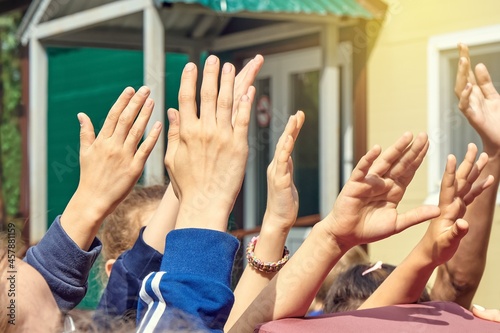 Group of people raises hands reaching up near cottage