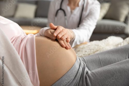 Antenatal care. Female doctor family therapist ob-gyn support comfort help young pregnant woman patient. Medic worker touching hand of expectant mother caressing her belly on checkup. Close up view