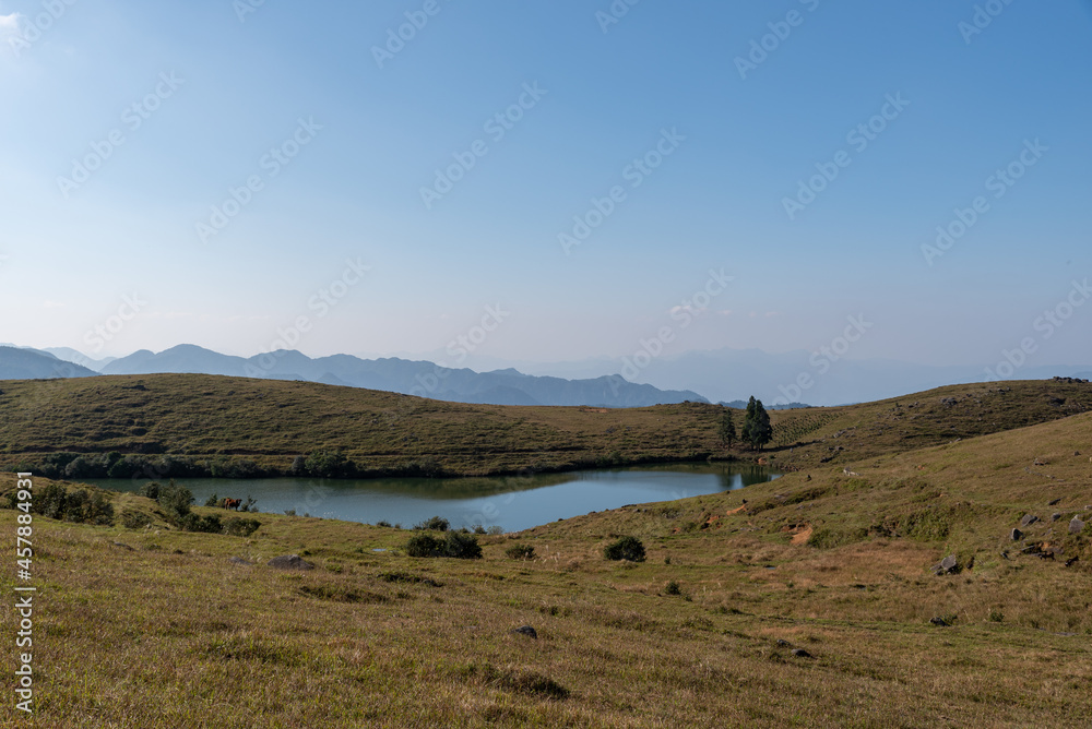Obraz premium The full view of the natural lake on the grassland, with blue sky, clear water and yellow grass