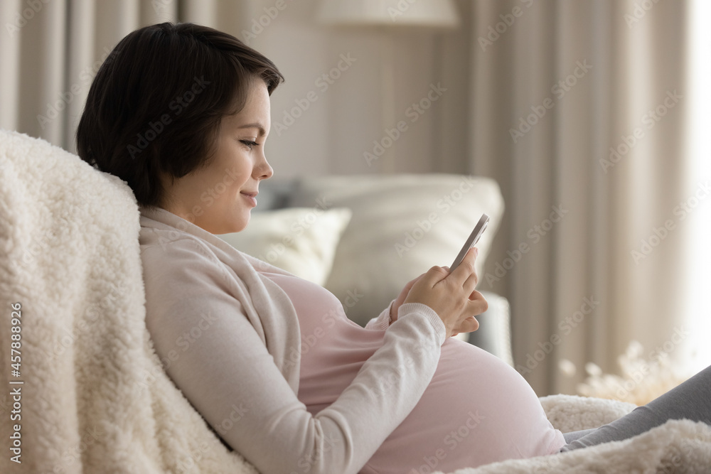 Baby blog. Interested young future mum blogging about pregnancy parenthood order goods for newborn at web shop online using cell. Expectant mom watch childbirth video on phone text message to husband Baby blog. Interested young future mum blogging about pregnancy parenthood order goods for newborn at web shop online using cell. Expectant mom watch childbirth video on phone text message to husband