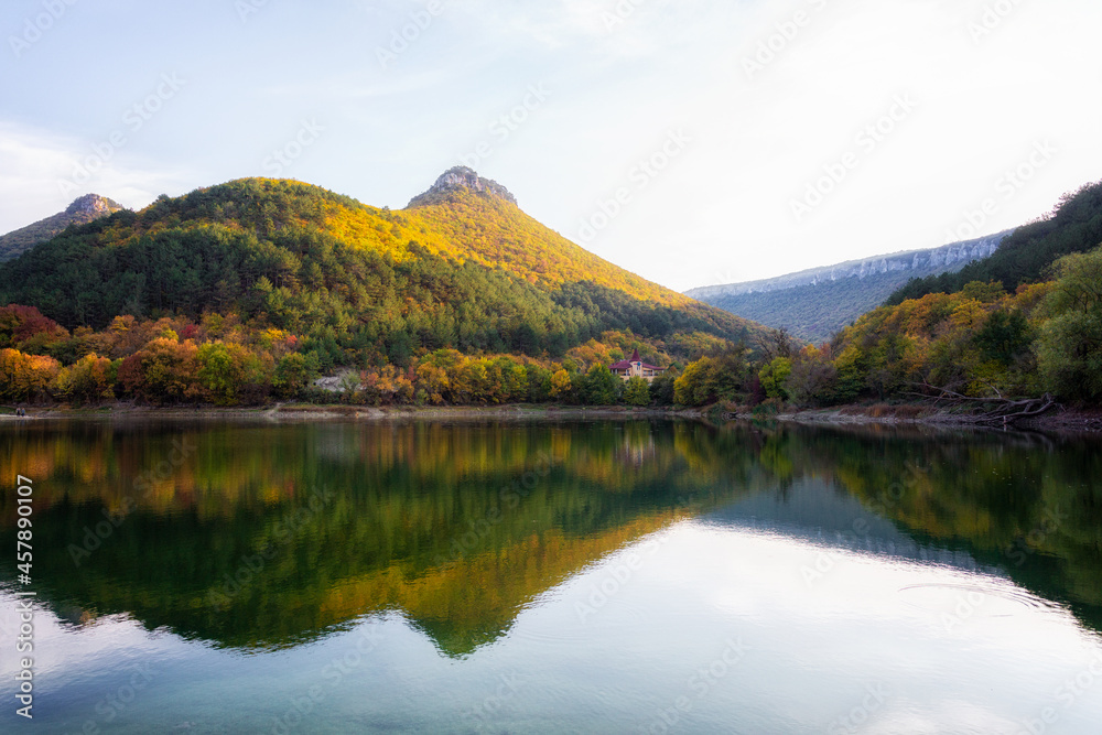 The building stands in the autumn forest in the mountains which are reflected in the lake of Mangup-Kale.. The building stands in the autumn forest in the mountains which are reflected in the lake of Mangup-Kale..