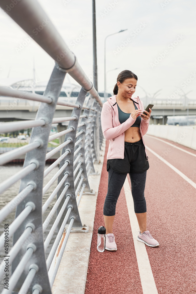 Young athlete texting a message on mobile phone during sports training on fresh air Young athlete texting a message on mobile phone during sports training on fresh air