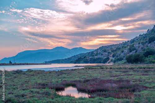 Beautiful summer landscape on sunset     colorful sky with clouds  reflecting in lake water  mountains on the horizon. Butrint  Albania.