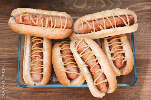 Group of tasty hotdogs with sausages and mustard over wooden background