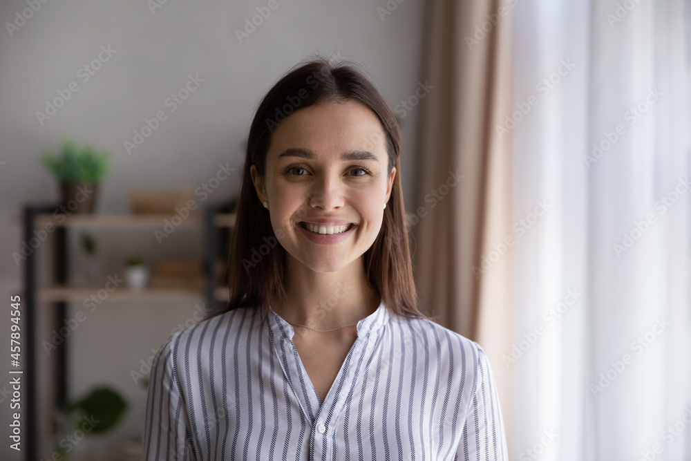 Head shot portrait confident businesswoman, successful entrepreneur, student looking at camera, happy beautiful young woman with healthy toothy smile posing for profile picture, standing at home