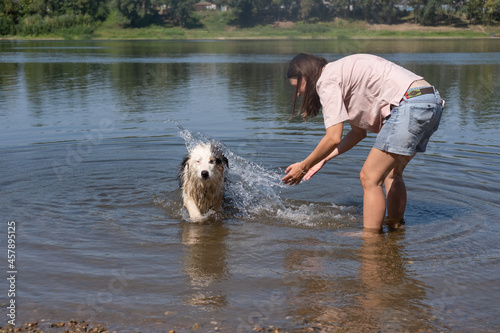 Woman play with australian shepherd dog in river outdoor. 