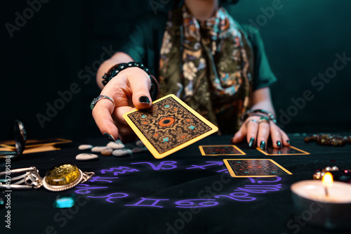 Fortune-telling on cards. The fortune teller hands over a Tarot card. The zodiac circle surrounds on the table. The concept of divination, astrology and esotericism photo