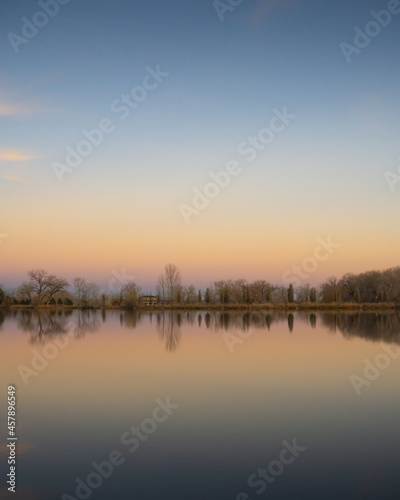 Trees reflect off a smooth pond at sunset