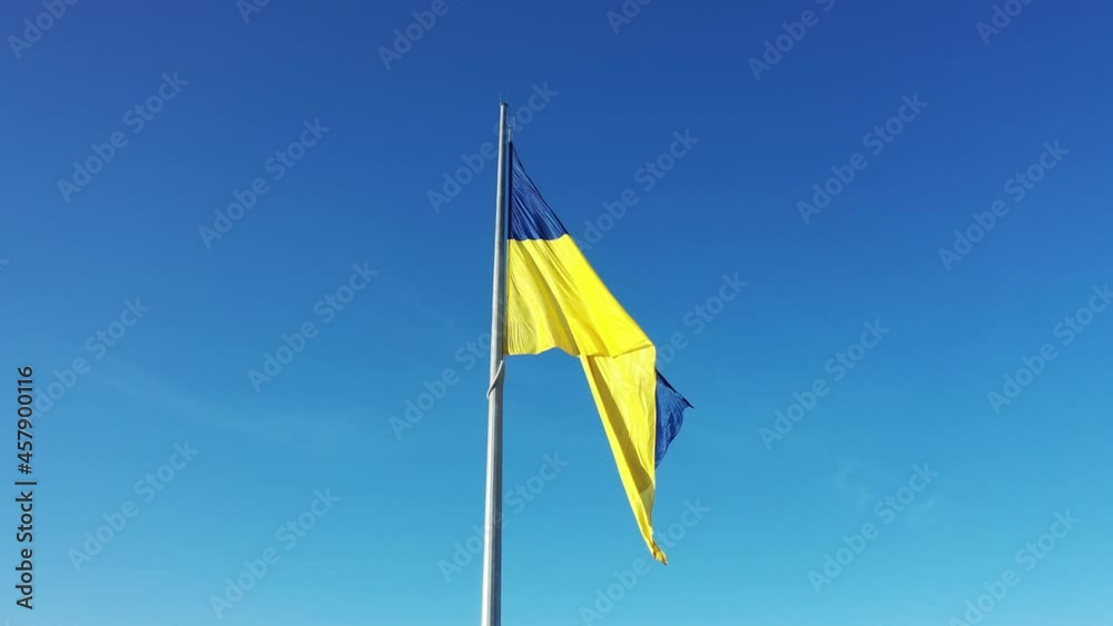 The flag of Ukraine develops on a flagpole against a background of clear sky The flag of Ukraine develops on a flagpole against a background of clear sky