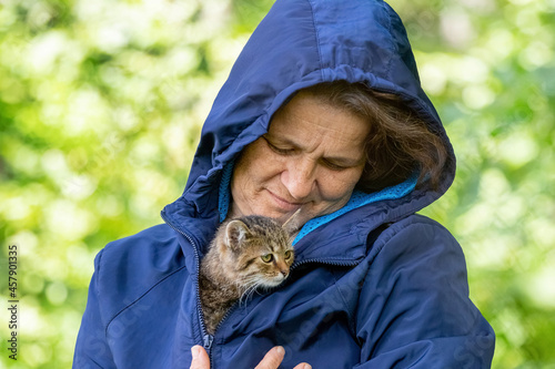 Canvas Print Elderly woman holding a small striped kitten, a kitten in the arms of a woman