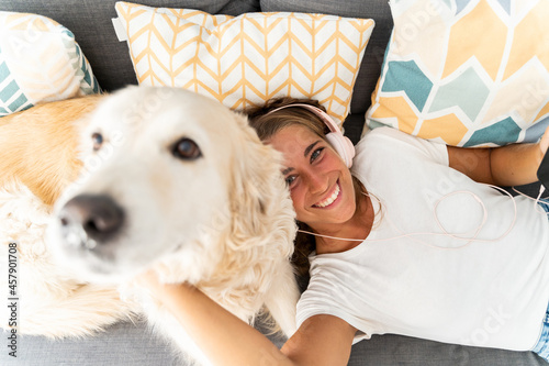 Sticker Selective focus of caucasian blonde woman playing with dog in the couch at home